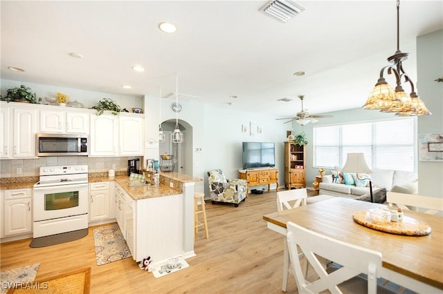 kitchen with light wood-type flooring, white electric stove, kitchen peninsula, pendant lighting, and white cabinets