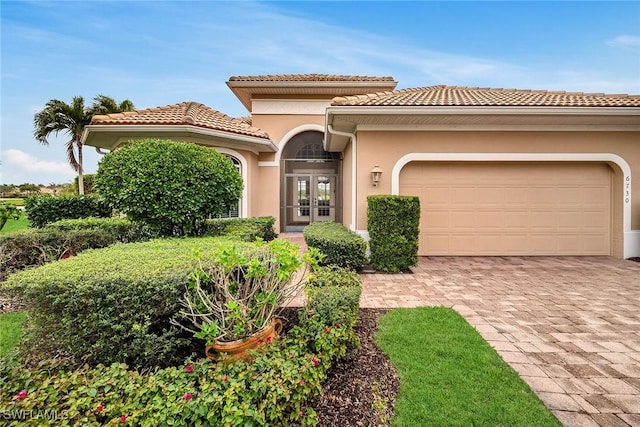 mediterranean / spanish-style home with a garage and french doors