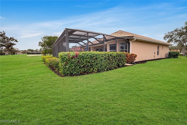 view of side of property featuring glass enclosure and a lawn