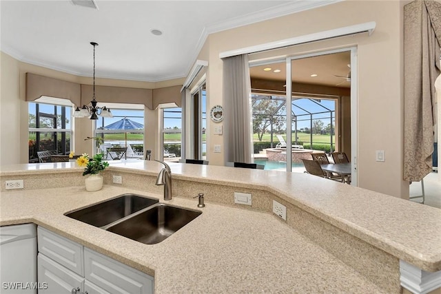 kitchen with pendant lighting, sink, white cabinetry, white dishwasher, and ornamental molding