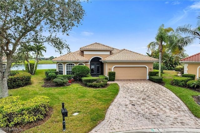 mediterranean / spanish-style home featuring a garage, a front yard, and a water view