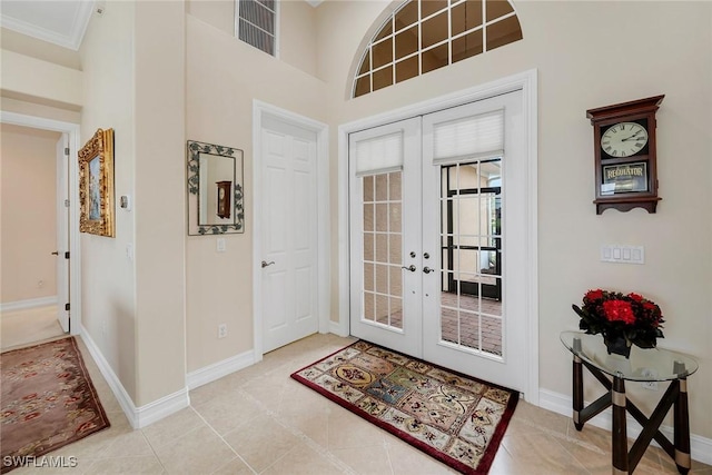 entryway featuring light tile patterned floors, crown molding, and french doors