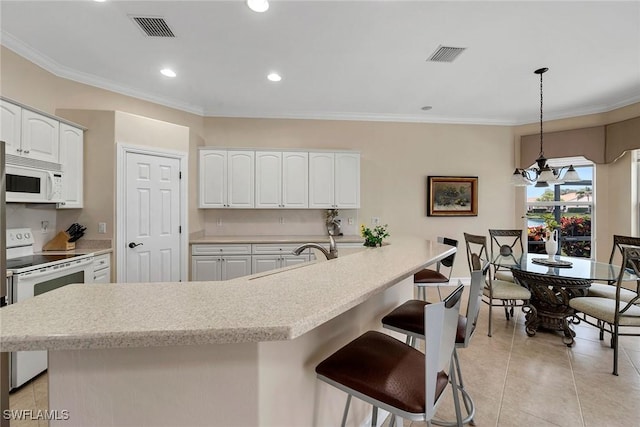 kitchen featuring sink, white appliances, white cabinetry, a center island with sink, and decorative light fixtures