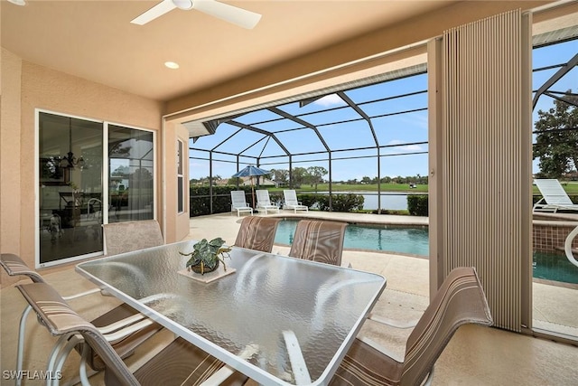 view of patio featuring a water view, ceiling fan, and a lanai