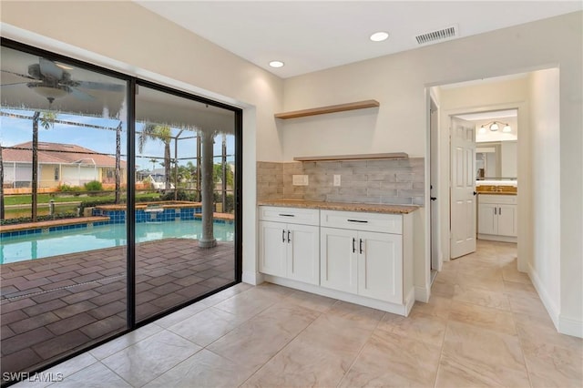 kitchen featuring white cabinetry, light stone counters, and decorative backsplash