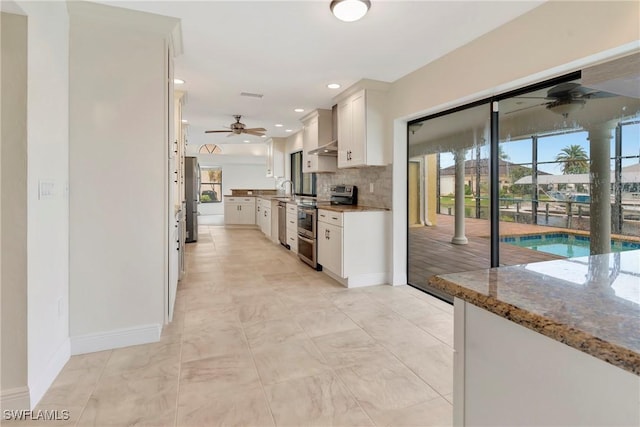 kitchen with plenty of natural light, white cabinets, decorative backsplash, stainless steel appliances, and light stone countertops