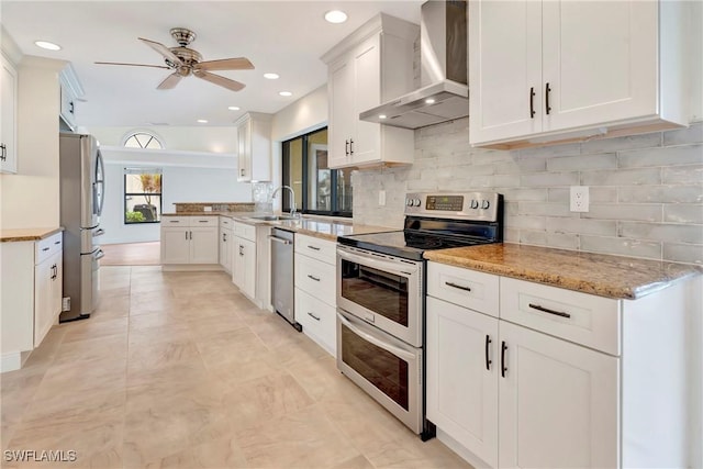 kitchen with sink, appliances with stainless steel finishes, white cabinets, decorative backsplash, and wall chimney exhaust hood