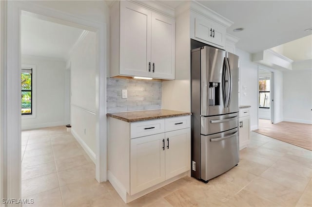 kitchen featuring white cabinetry, tasteful backsplash, dark stone countertops, ornamental molding, and stainless steel fridge