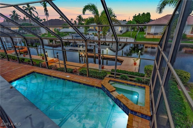 pool at dusk featuring an in ground hot tub and a water view