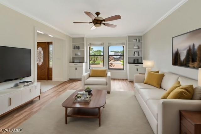 living room featuring built in shelves, light hardwood / wood-style flooring, ornamental molding, and ceiling fan