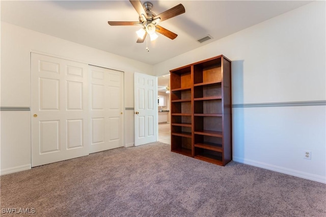 unfurnished bedroom with a closet, visible vents, a ceiling fan, carpet flooring, and baseboards