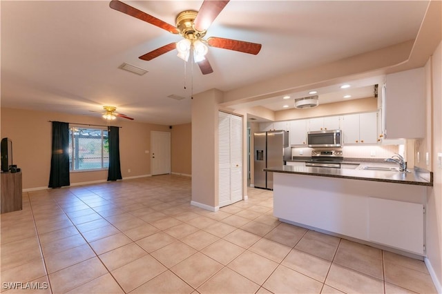 kitchen with stainless steel appliances, open floor plan, white cabinets, a sink, and light tile patterned flooring