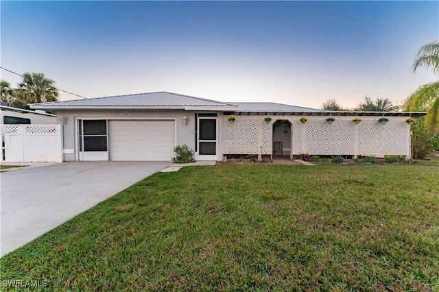 ranch-style home with a front yard, metal roof, driveway, and an attached garage