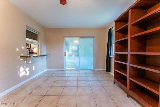 empty room with light tile patterned floors and baseboards