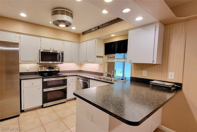 kitchen featuring appliances with stainless steel finishes, dark countertops, white cabinetry, and a peninsula