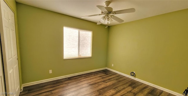 spare room featuring dark wood finished floors, a ceiling fan, and baseboards