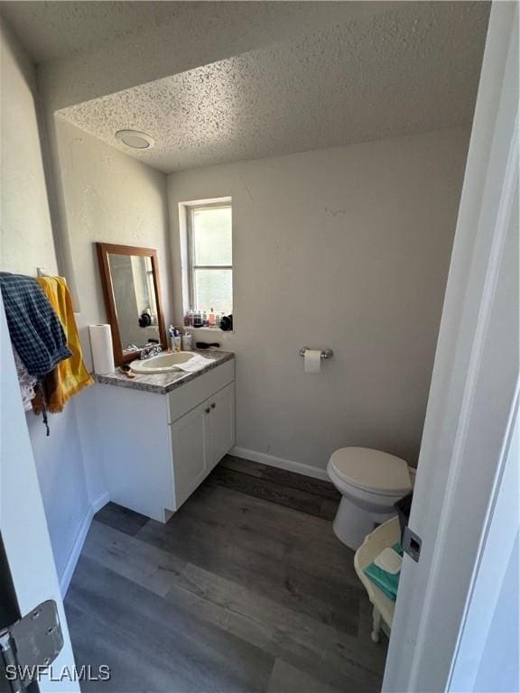 bathroom featuring wood-type flooring, vanity, a textured ceiling, and toilet