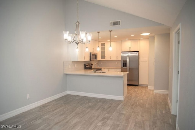 17291 Timber Oak Ln, Fort Myers, FL 33908 - kitchen with pendant lighting, light hardwood / wood-style flooring, stainless steel appliances, white cabinets, and kitchen peninsula