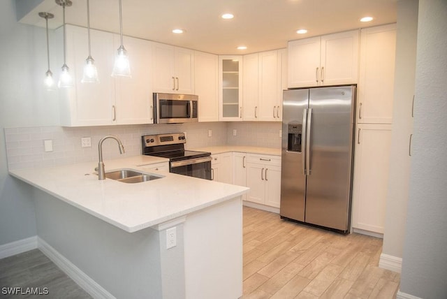 kitchen with sink, hanging light fixtures, appliances with stainless steel finishes, kitchen peninsula, and white cabinets