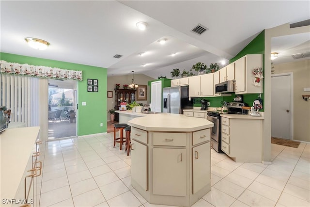 kitchen with lofted ceiling, light tile patterned floors, stainless steel appliances, a center island, and a kitchen bar