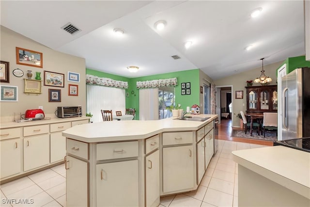 kitchen with vaulted ceiling, appliances with stainless steel finishes, sink, a center island with sink, and cream cabinetry