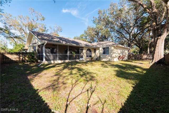 rear view of property featuring a sunroom and a lawn