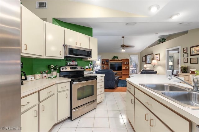 kitchen with light tile patterned flooring, lofted ceiling, sink, ceiling fan, and stainless steel appliances