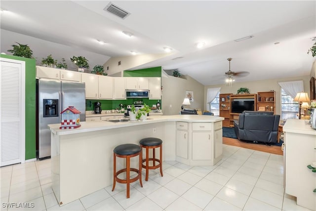 kitchen with vaulted ceiling, light tile patterned floors, appliances with stainless steel finishes, kitchen peninsula, and ceiling fan