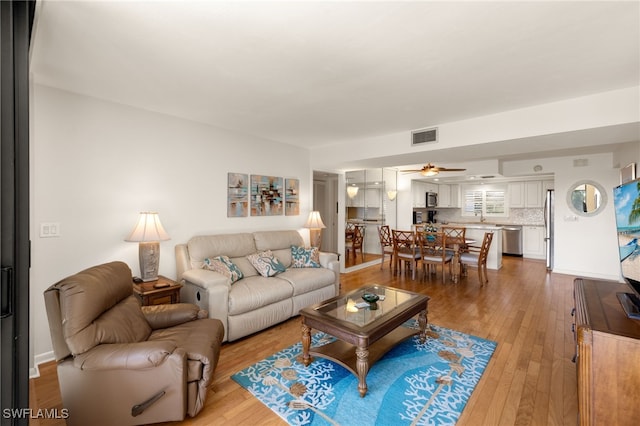 living room featuring ceiling fan, wood-type flooring, and sink