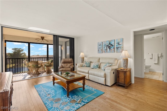 living room featuring ceiling fan, floor to ceiling windows, and light hardwood / wood-style flooring