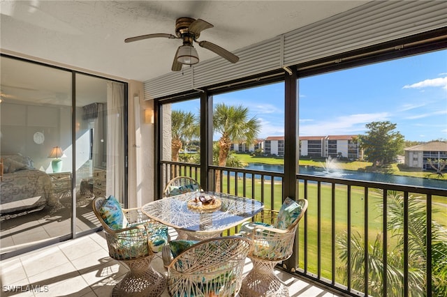 sunroom / solarium featuring a water view and ceiling fan