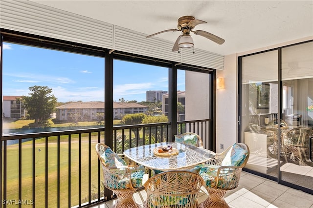 sunroom / solarium with ceiling fan and a water view