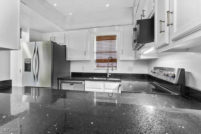 kitchen with stainless steel appliances, white cabinetry, sink, and dark stone countertops