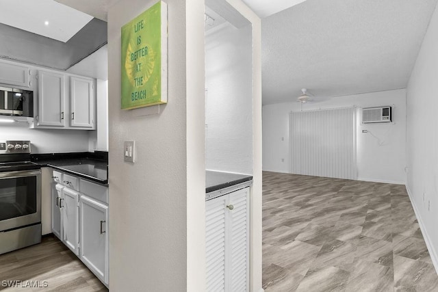 kitchen featuring stainless steel appliances, white cabinetry, and an AC wall unit