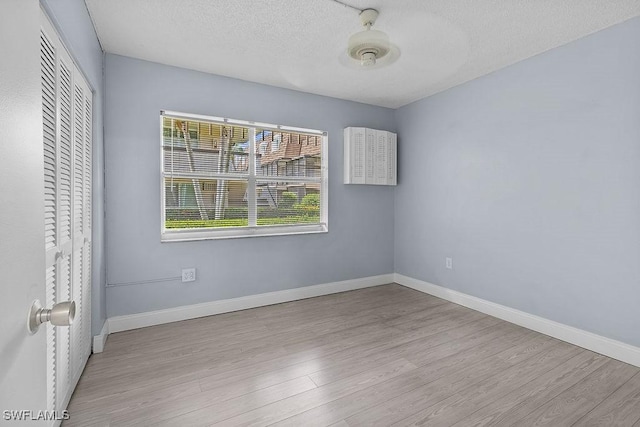 unfurnished bedroom featuring light hardwood / wood-style floors, a closet, and a textured ceiling