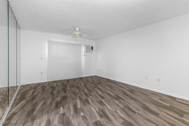 unfurnished room featuring dark wood-type flooring, a wall mounted AC, a textured ceiling, and ceiling fan