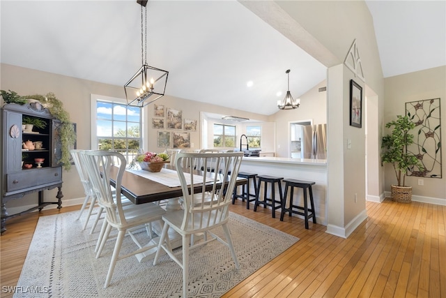 dining space featuring plenty of natural light, a chandelier, vaulted ceiling, and light wood-type flooring