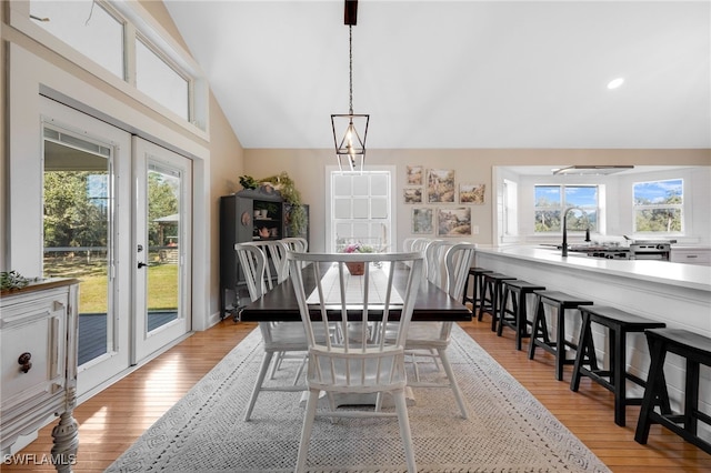 dining area with lofted ceiling, a healthy amount of sunlight, sink, and light wood-type flooring