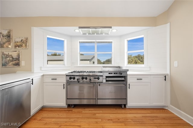 kitchen with extractor fan, light hardwood / wood-style flooring, stainless steel appliances, and white cabinets