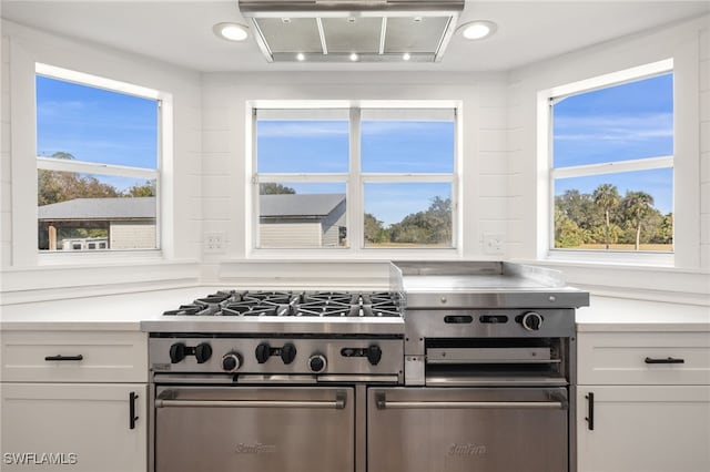 kitchen featuring white cabinetry, stainless steel range, and ventilation hood