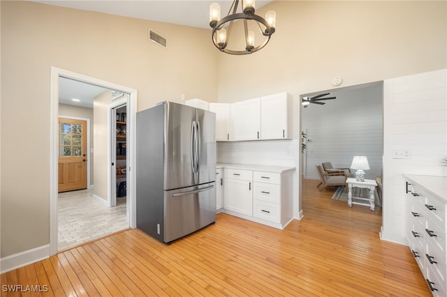 kitchen with white cabinetry, pendant lighting, stainless steel fridge, and light wood-type flooring