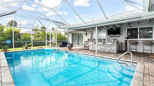 view of swimming pool featuring ceiling fan, a lanai, an outdoor bar, and a patio area