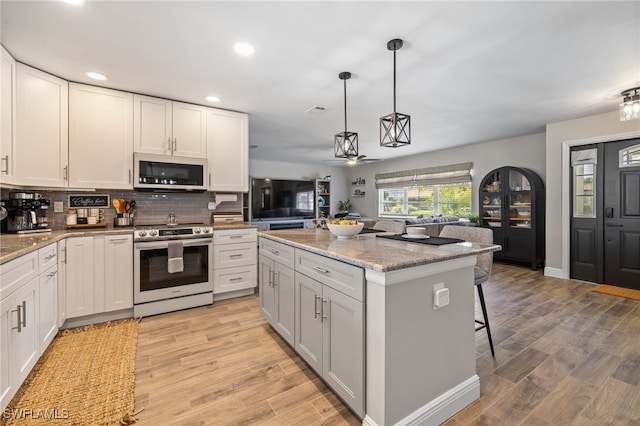 kitchen with electric stove, pendant lighting, a center island, light stone counters, and white cabinets