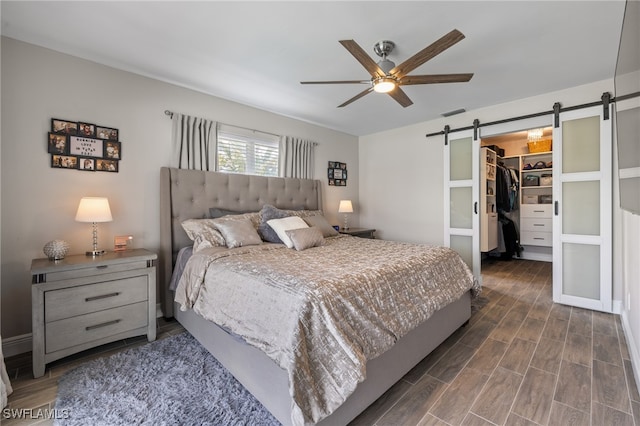 bedroom with a closet, a spacious closet, a barn door, and ceiling fan