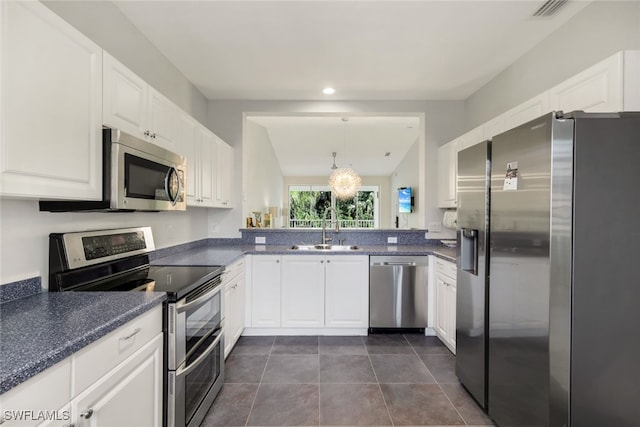 kitchen featuring sink, white cabinetry, dark tile patterned floors, pendant lighting, and stainless steel appliances