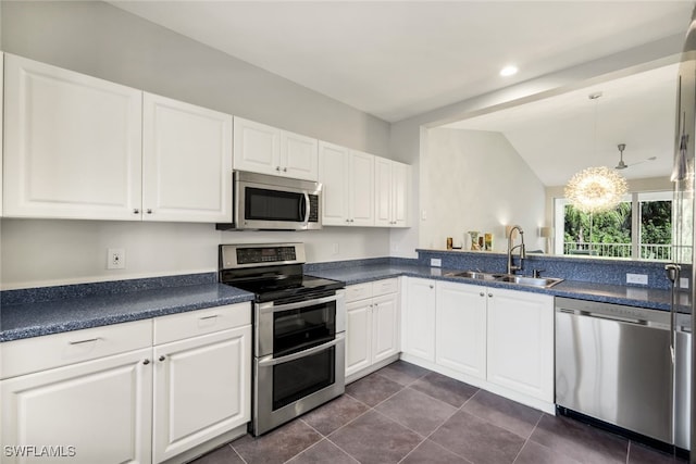 kitchen with appliances with stainless steel finishes, decorative light fixtures, white cabinetry, sink, and dark tile patterned floors