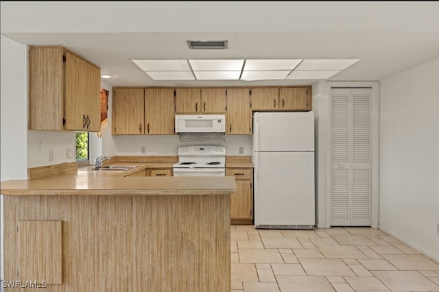 kitchen with white appliances, kitchen peninsula, and sink