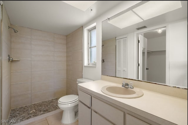 bathroom with vanity, tile patterned flooring, toilet, and a tile shower