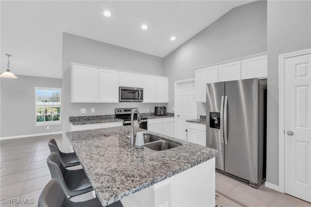 kitchen with appliances with stainless steel finishes, a kitchen island with sink, hanging light fixtures, and white cabinets