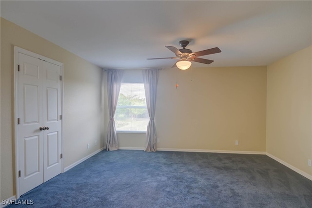 empty room featuring ceiling fan and dark carpet